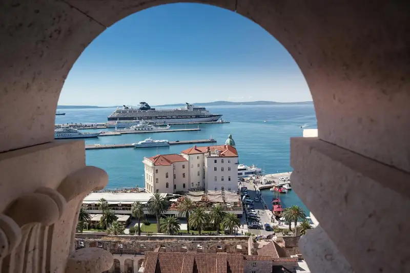 View of a cruise ship in Split, Croatia from an arched stone window, showcasing summer sea beauty.