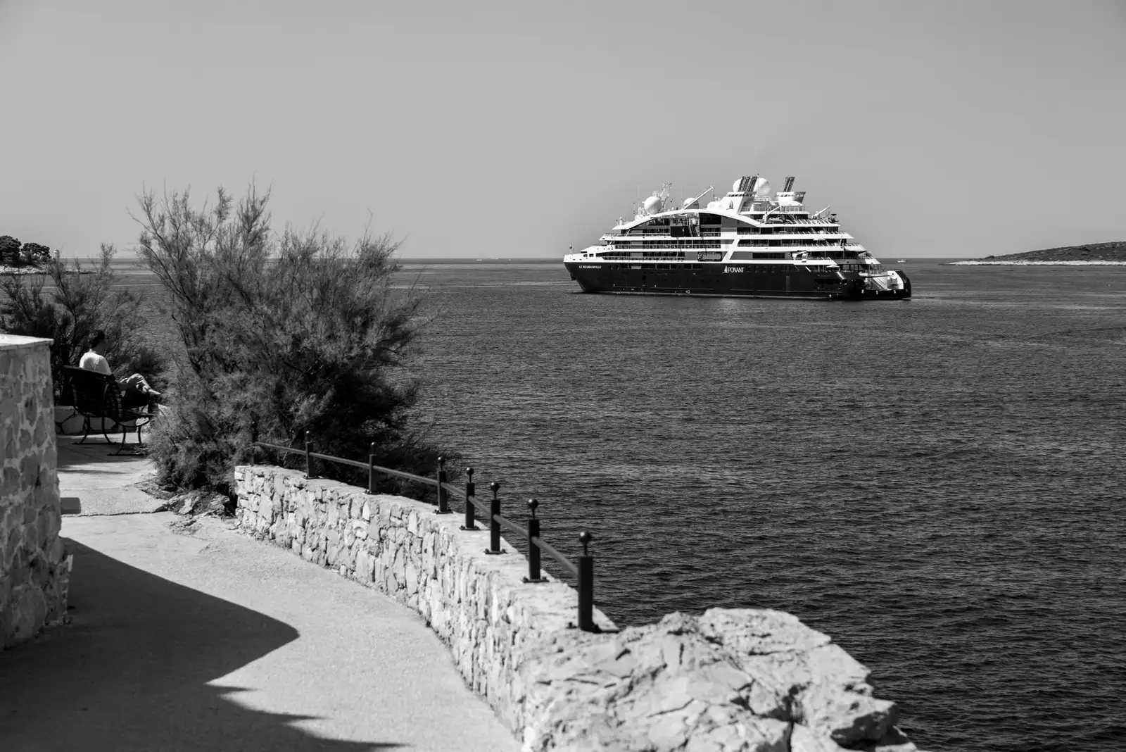 Black and white photo of a luxury cruise ship near Primošten, Croatia, with a stone walkway.