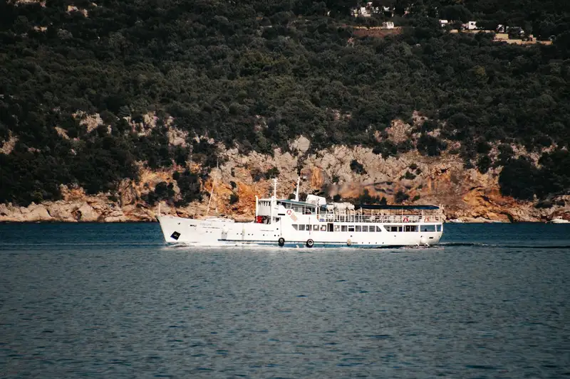 A ferry cruises through the Adriatic Sea near Lopud Island, Croatia, showcasing stunning natural cliffs.