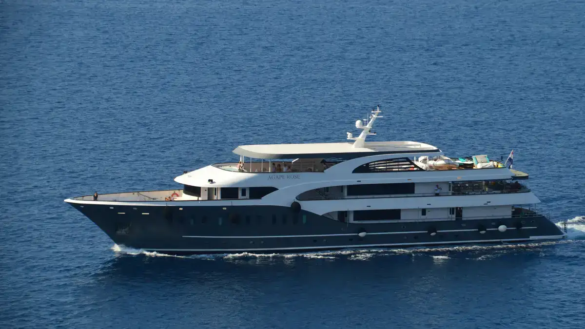 Small ship cruising in Croatia: luxury yacht sailing calm blue waters under clear sky, serene elegance.
