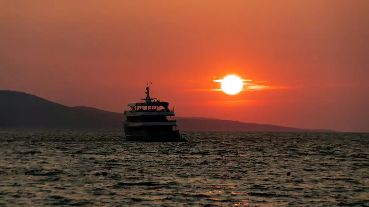 A boat navigates the calm sea during a stunning sunset near Makarska, Croatia.